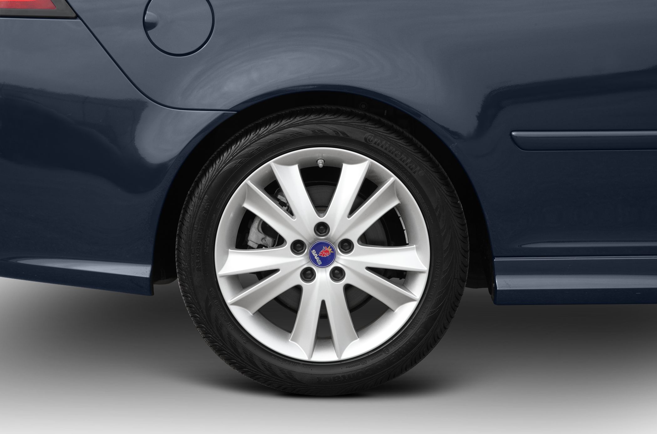 Close-up of a multi-spoke alloy rear wheel and tire on a dark blue body