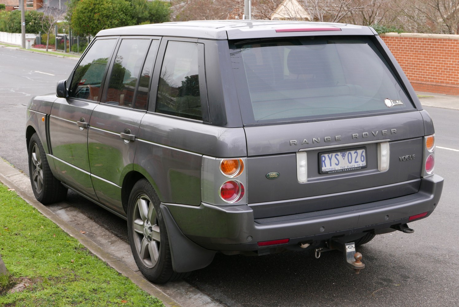 Rear of a luxury SUV with vertical tail lights and a tow hitch.