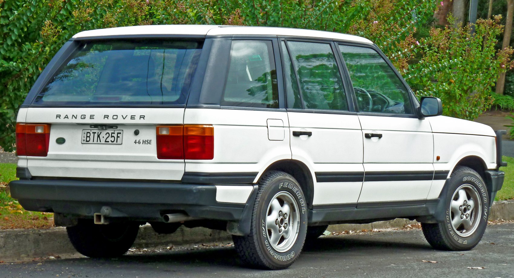 Rear and side profile of a classic white mid-1990s SUV