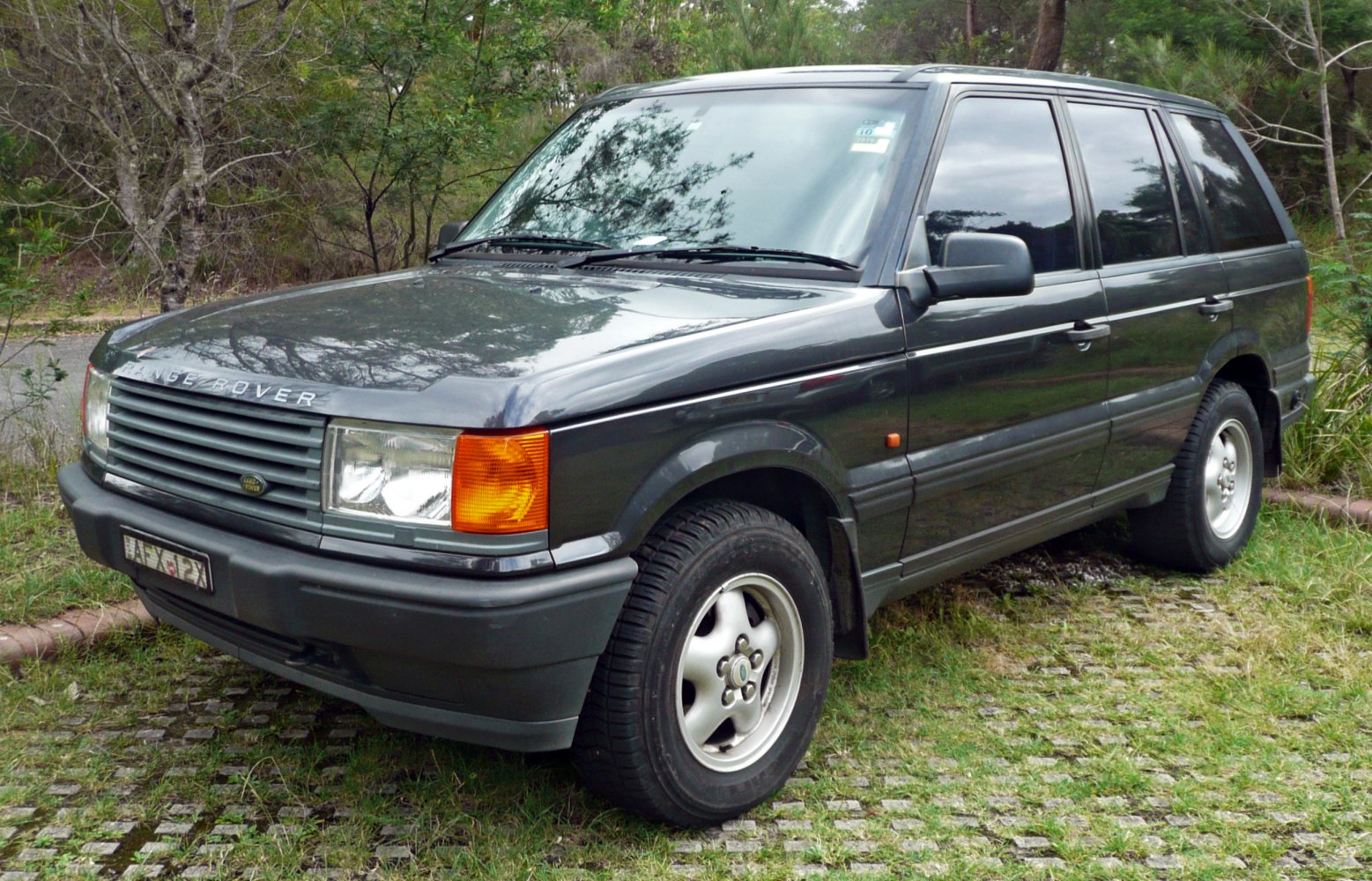 Boxy SUV with distinctive front grille and tinted windows in natural setting