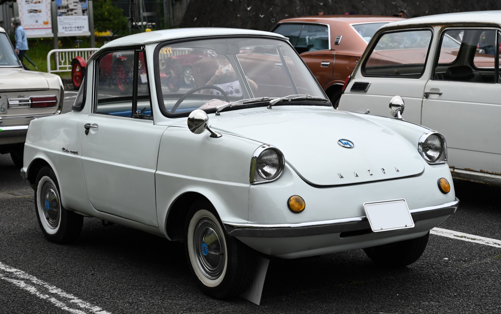Compact rounded vintage microcar with chrome side mirrors and classic headlamps