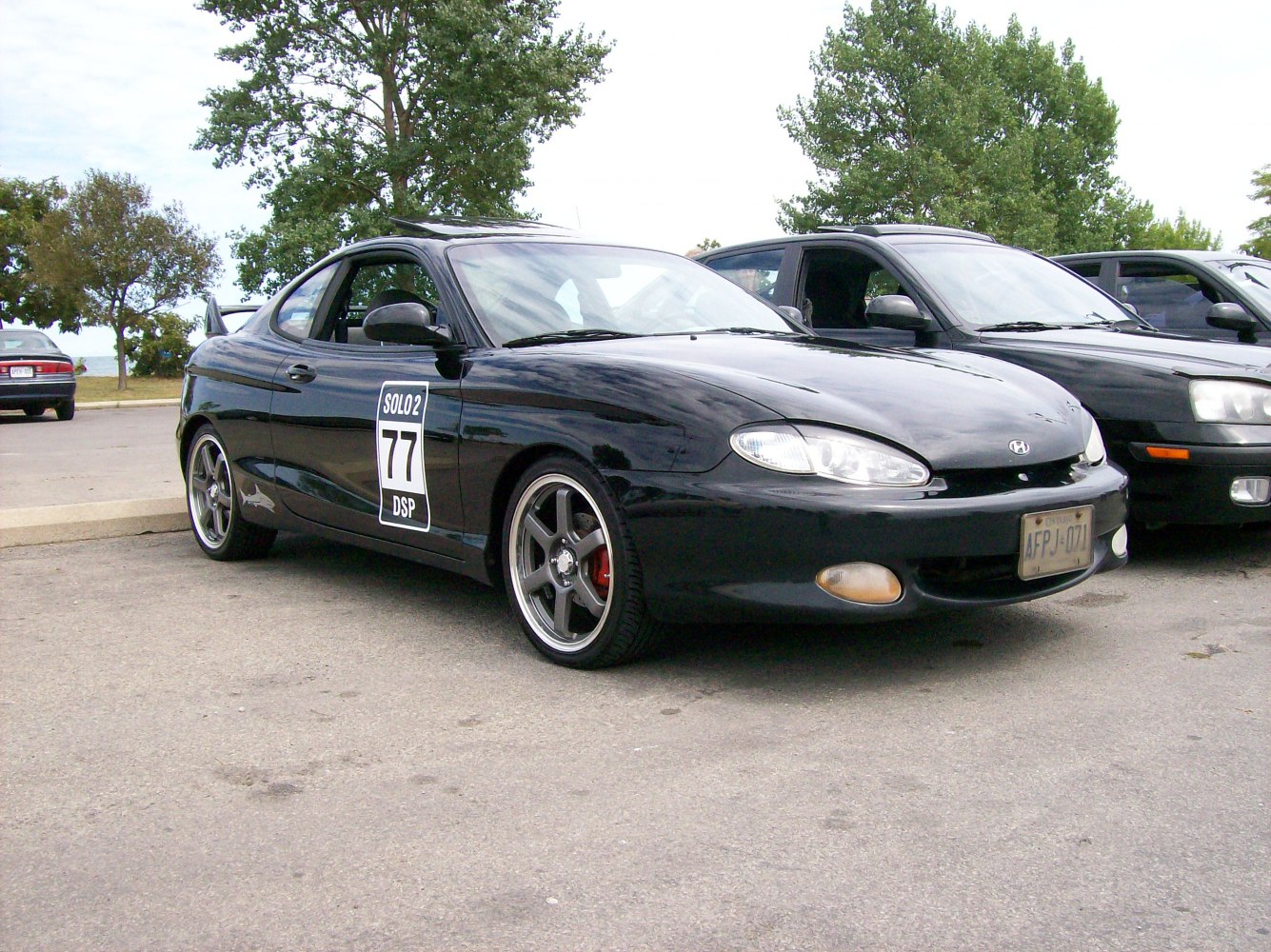 Front-side view of a black coupe with racing decal and sporty wheels