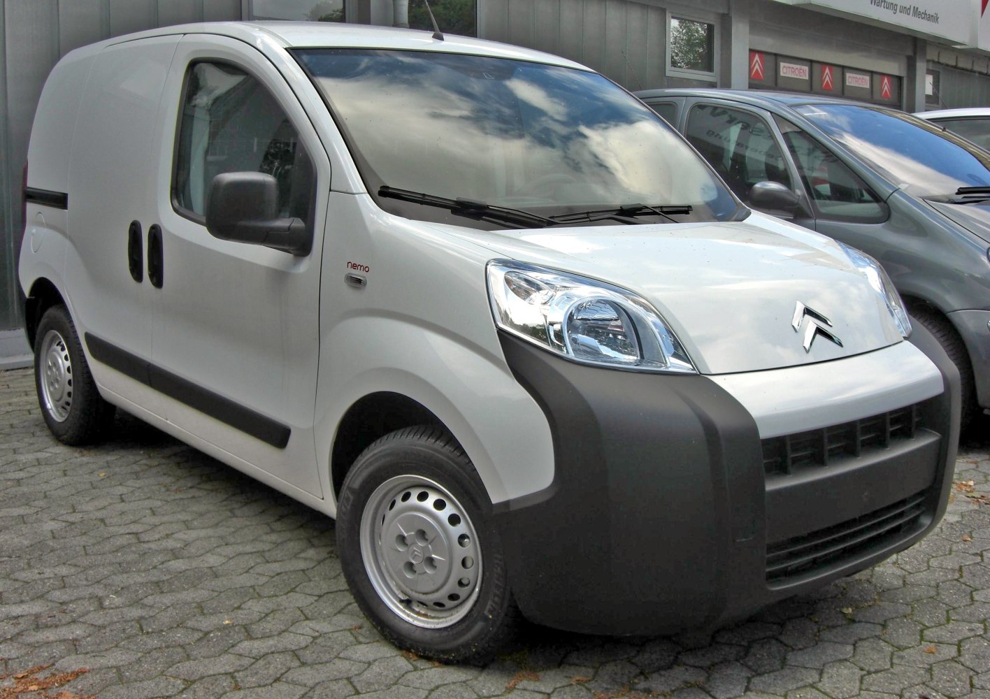 Compact white panel van with unique black front bumper and sliding side door
