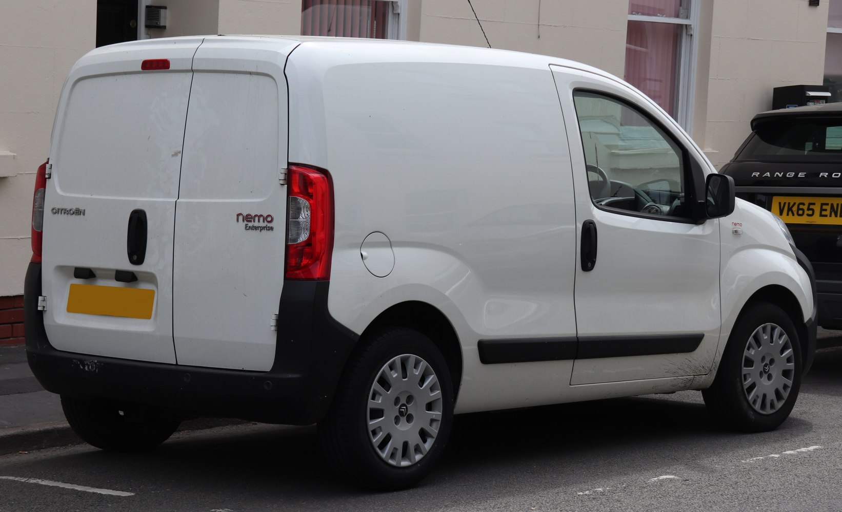Rear side view of a white panel van with dual cargo doors and compact design