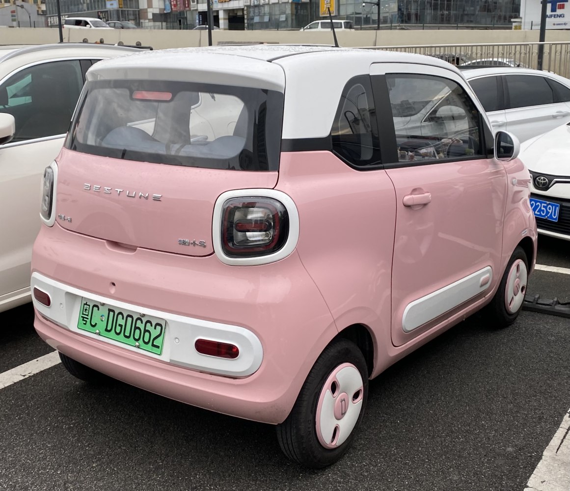 Compact pink and white two-tone electric citycar with distinctive rounded taillights