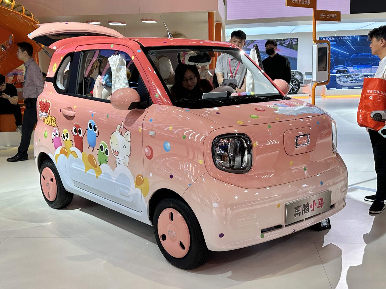 Compact pink electric vehicle with cartoon character decals and rounded headlights