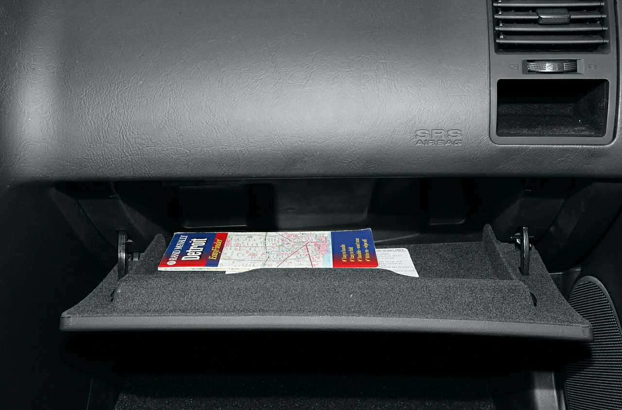 Open glove compartment with map and SRS airbag panel inside car interior