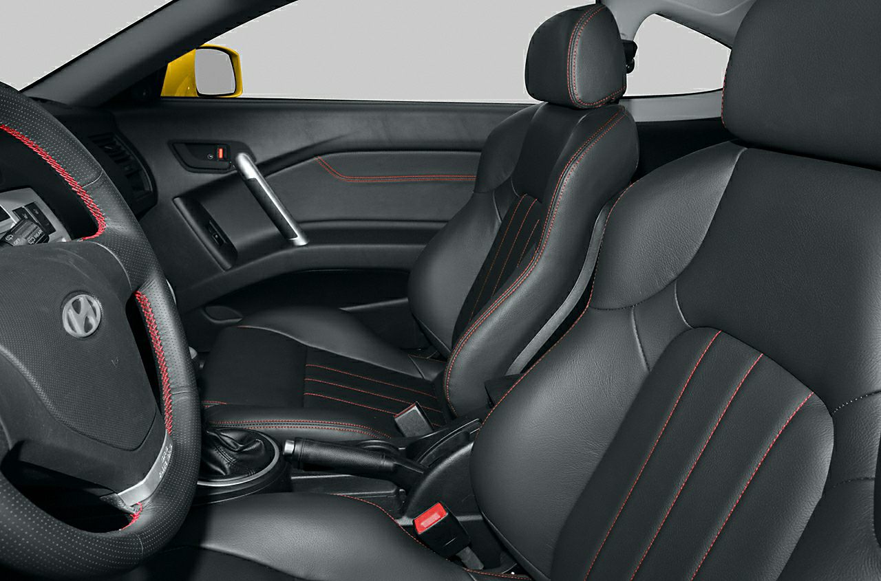 Black leather car seats with red stitching and leather-trimmed steering wheel