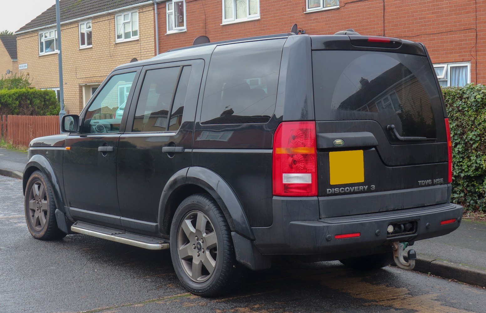 Black SUV rear side view with tow hitch and side steps