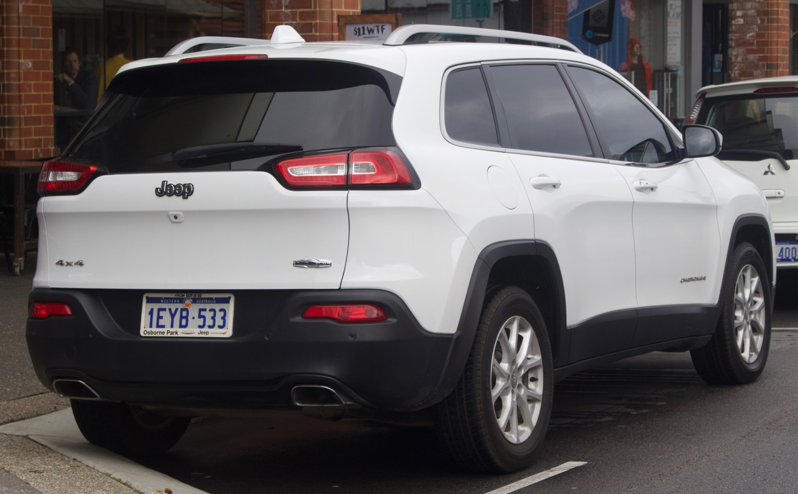 Rear and side view of white SUV with dual exhaust and tinted windows
