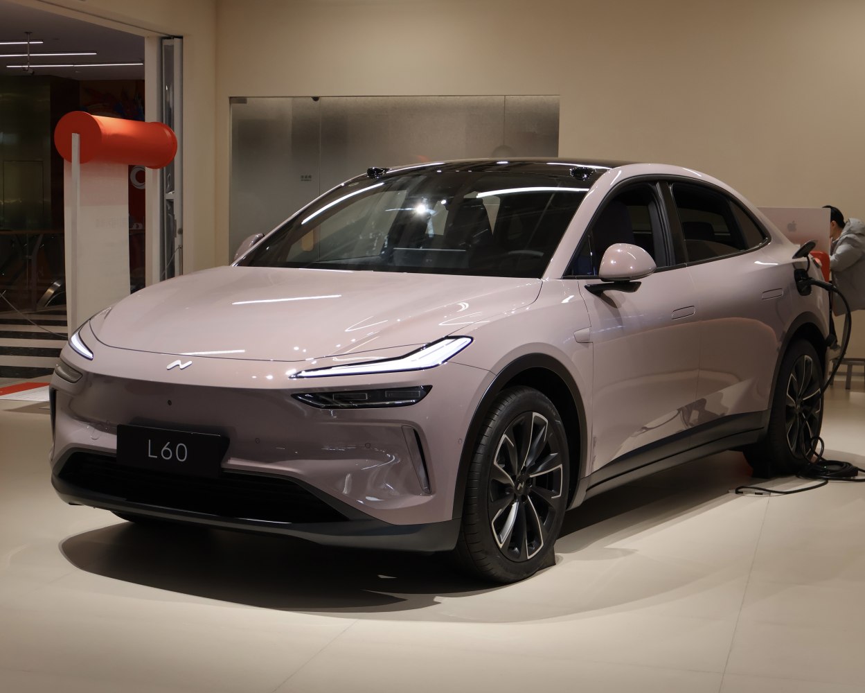 Electric sedan with sleek front design and charger plugged in