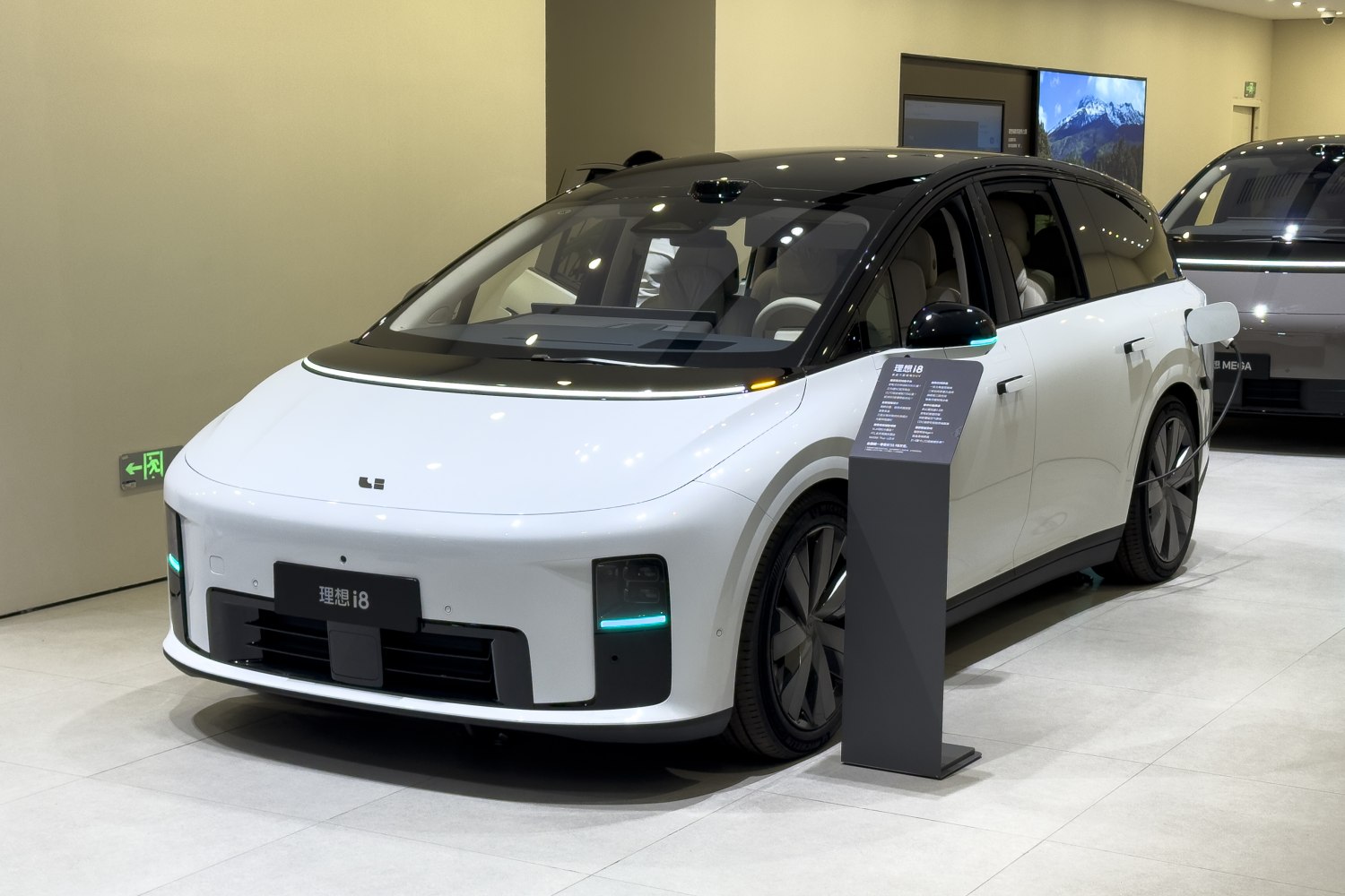 Front and side view of electric SUV with charging cable attached.