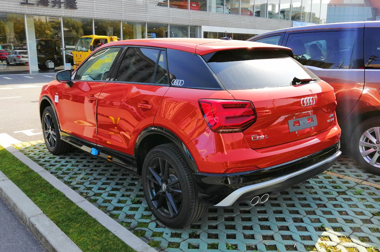 Red compact SUV rear-side with dual exhaust and black wheels