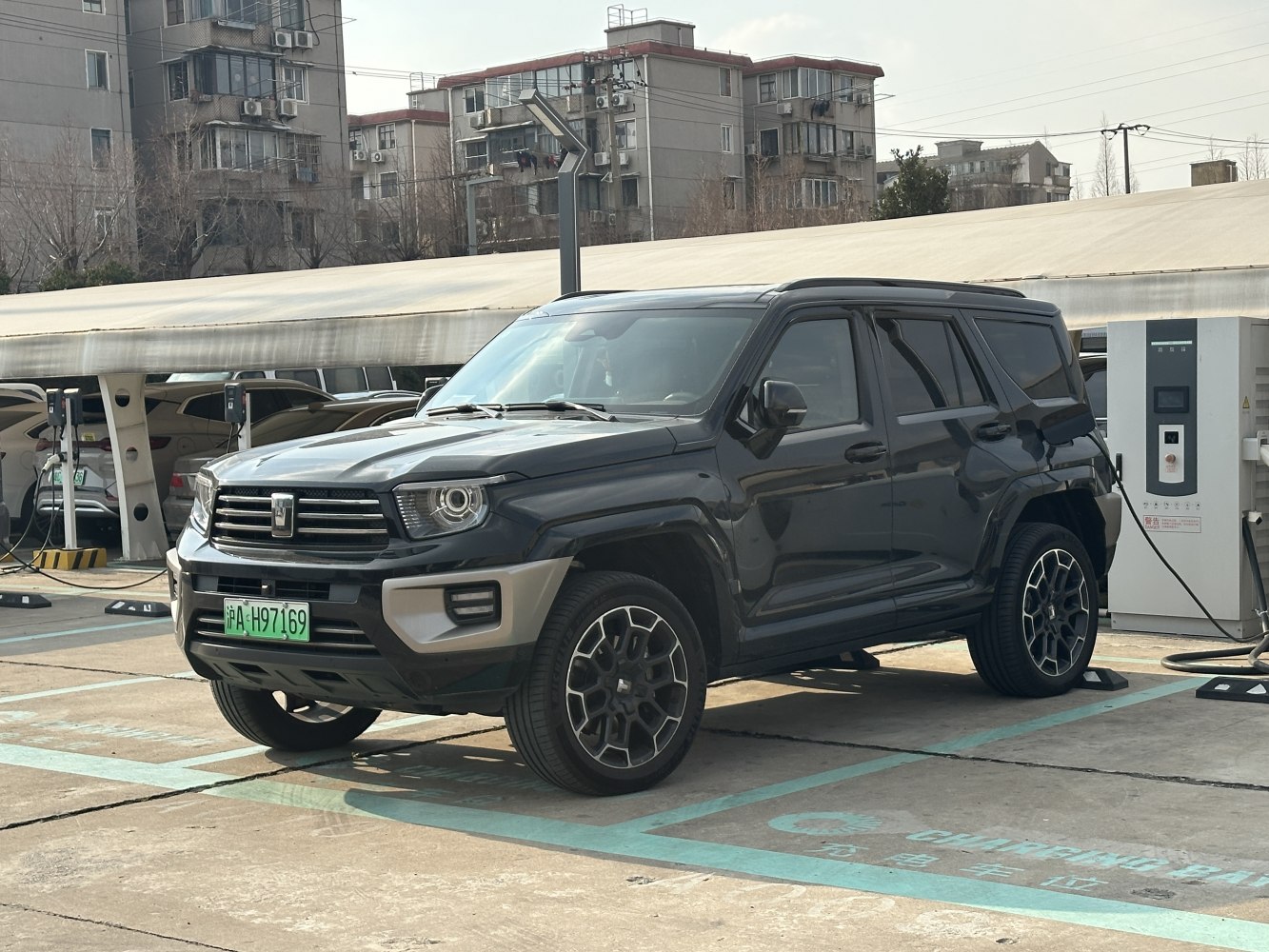 Black SUV plugged into electric charging station in urban area