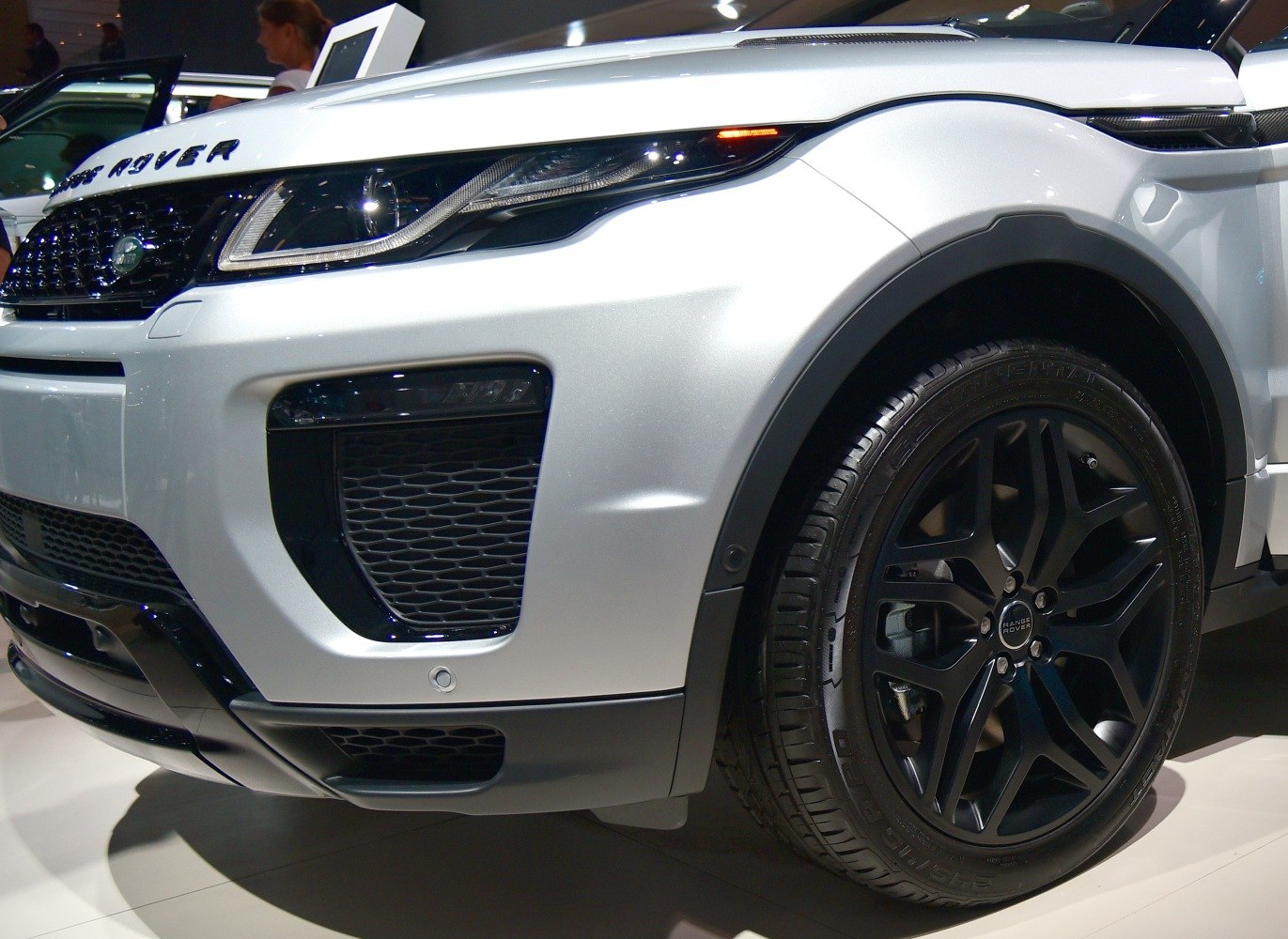 Front headlight and black alloy wheel close-up with grille and bumper details
