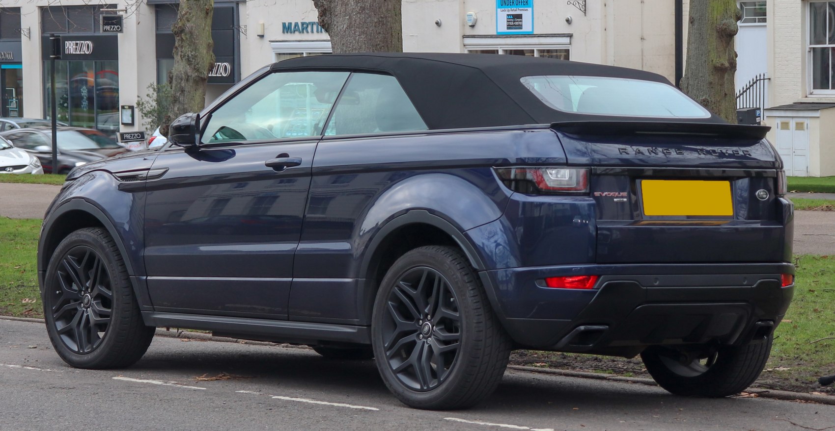 Rear side view of convertible SUV with soft top roof and black rims