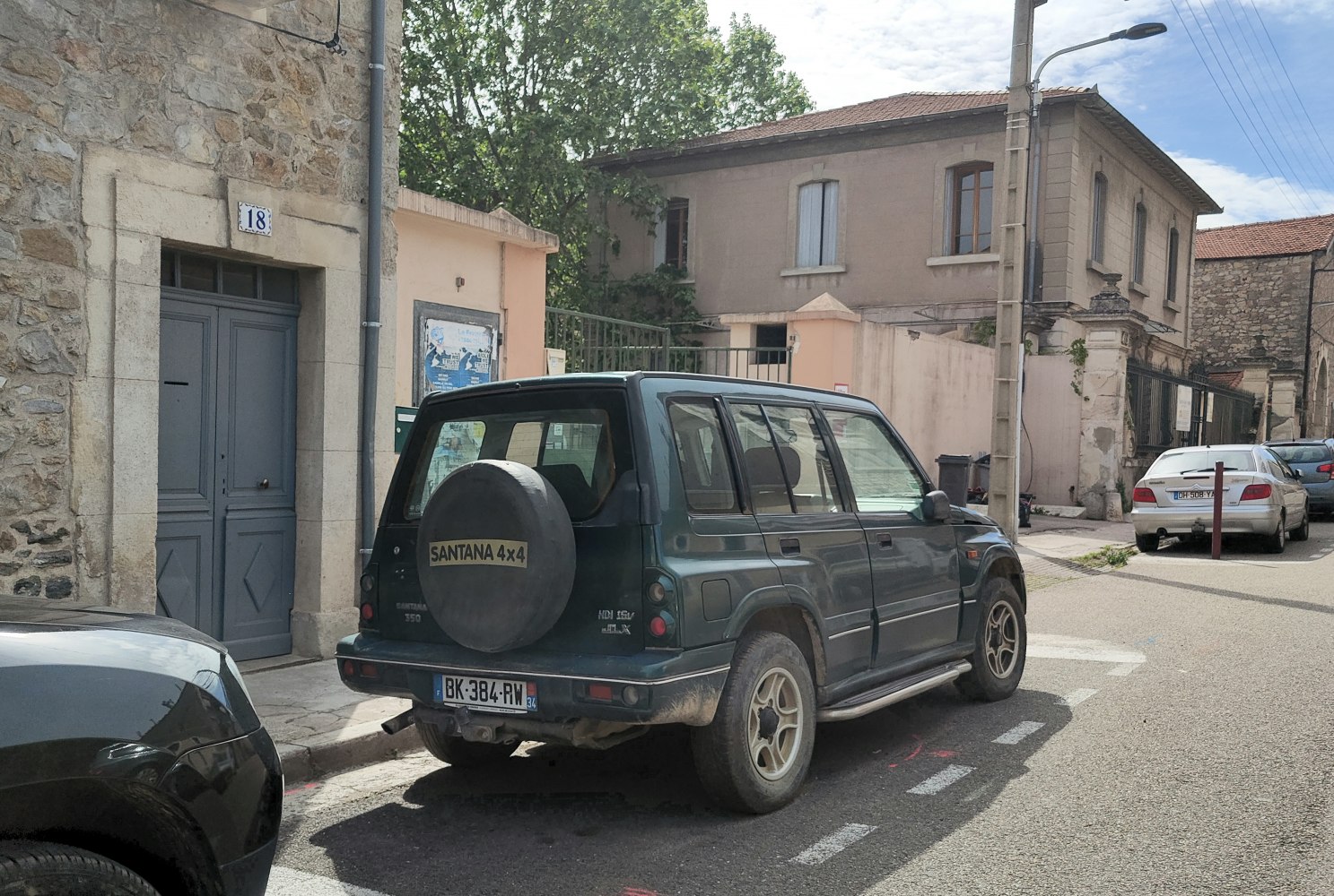 Boxy 4x4 SUV rear side with spare tire on tailgate and alloy wheels.