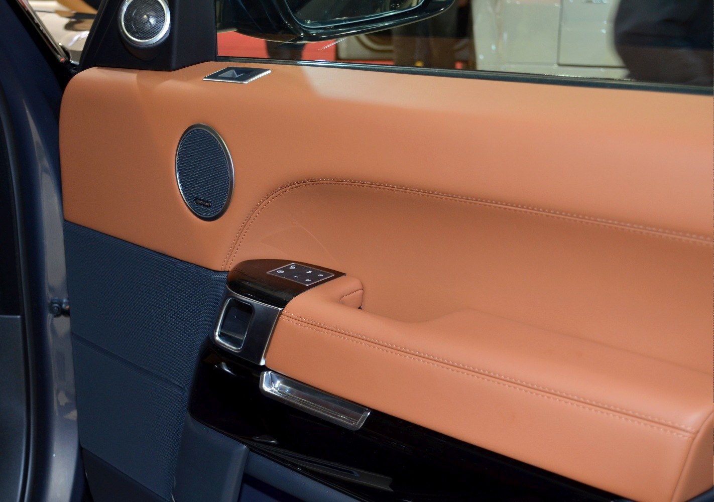 Luxury tan leather door panel with premium speaker and window controls