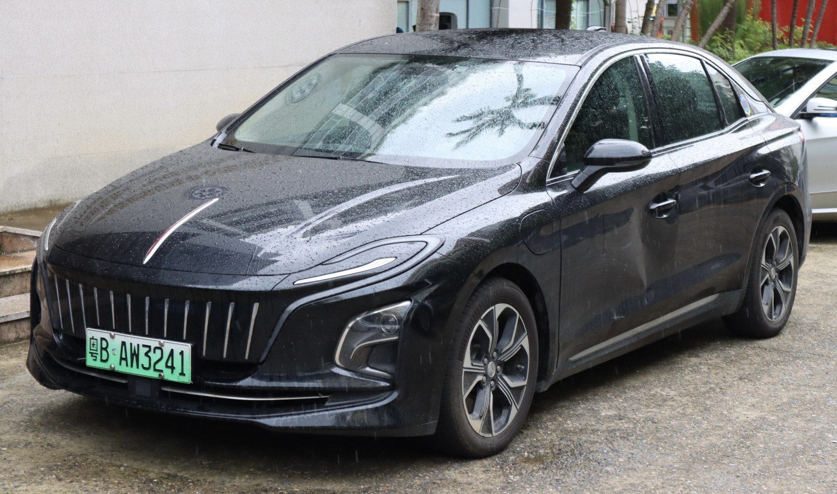 Sleek electric sedan with vertical grille and LED headlights in urban setting.