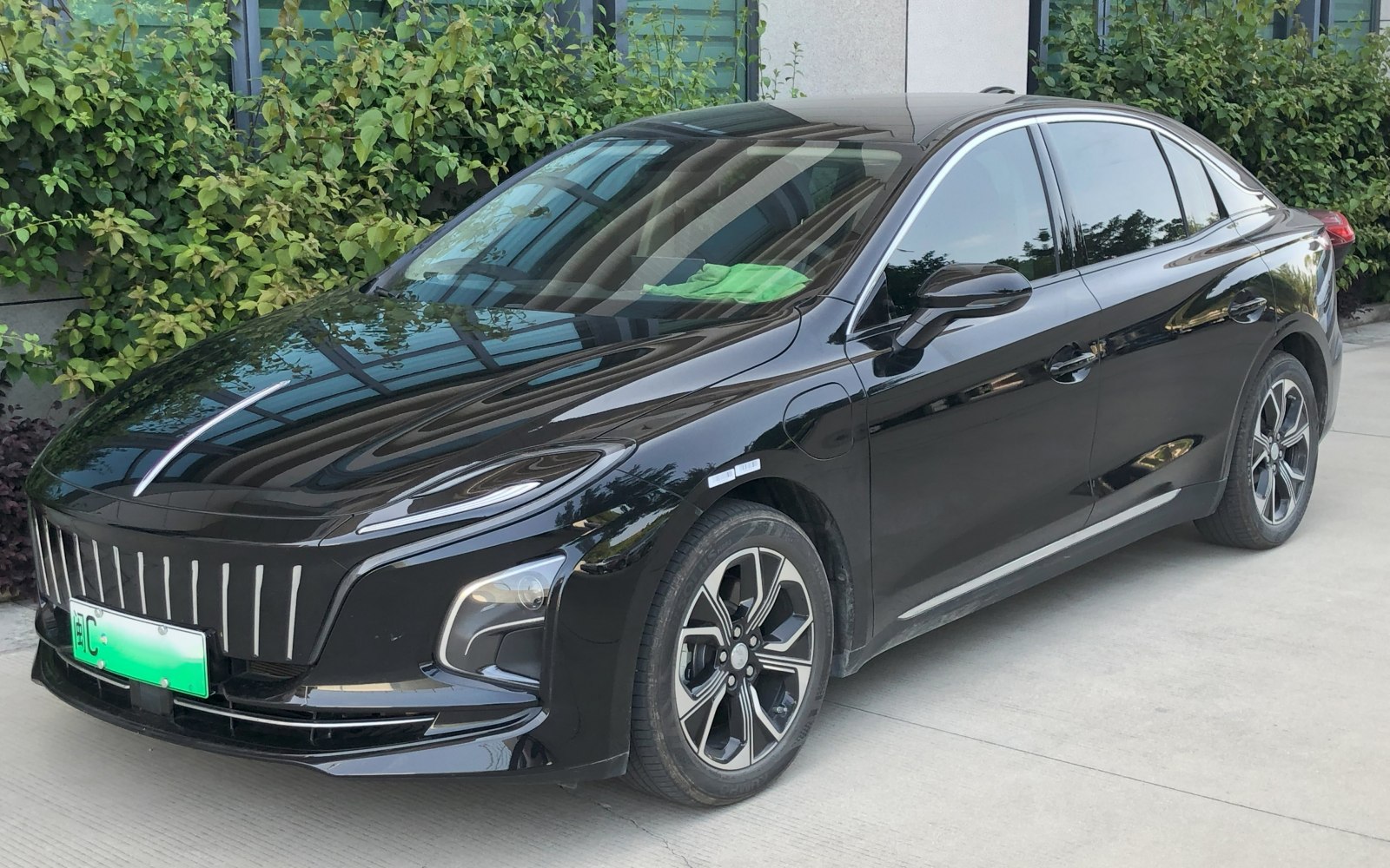 Front side view of a black electric sedan with LED headlights and distinctive grille