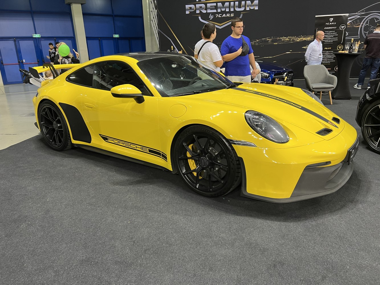 Yellow Porsche coupe with black racing stripes and aerodynamic rear wing