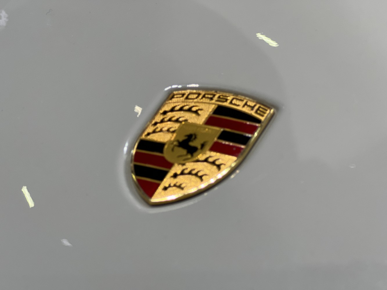 Close-up of a Porsche emblem on a light surface