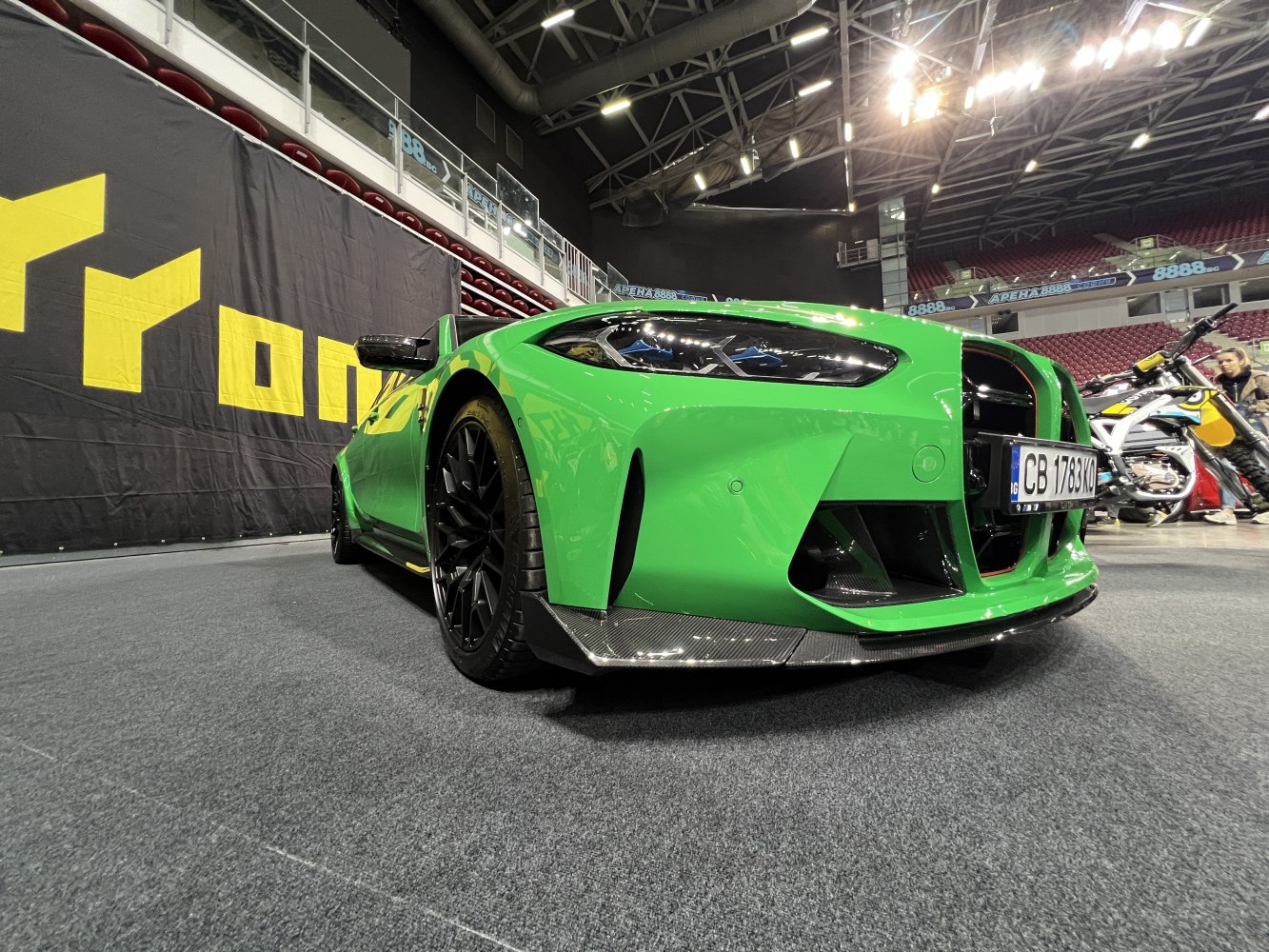 Aggressive green sports sedan front with carbon fiber splitter and black wheels