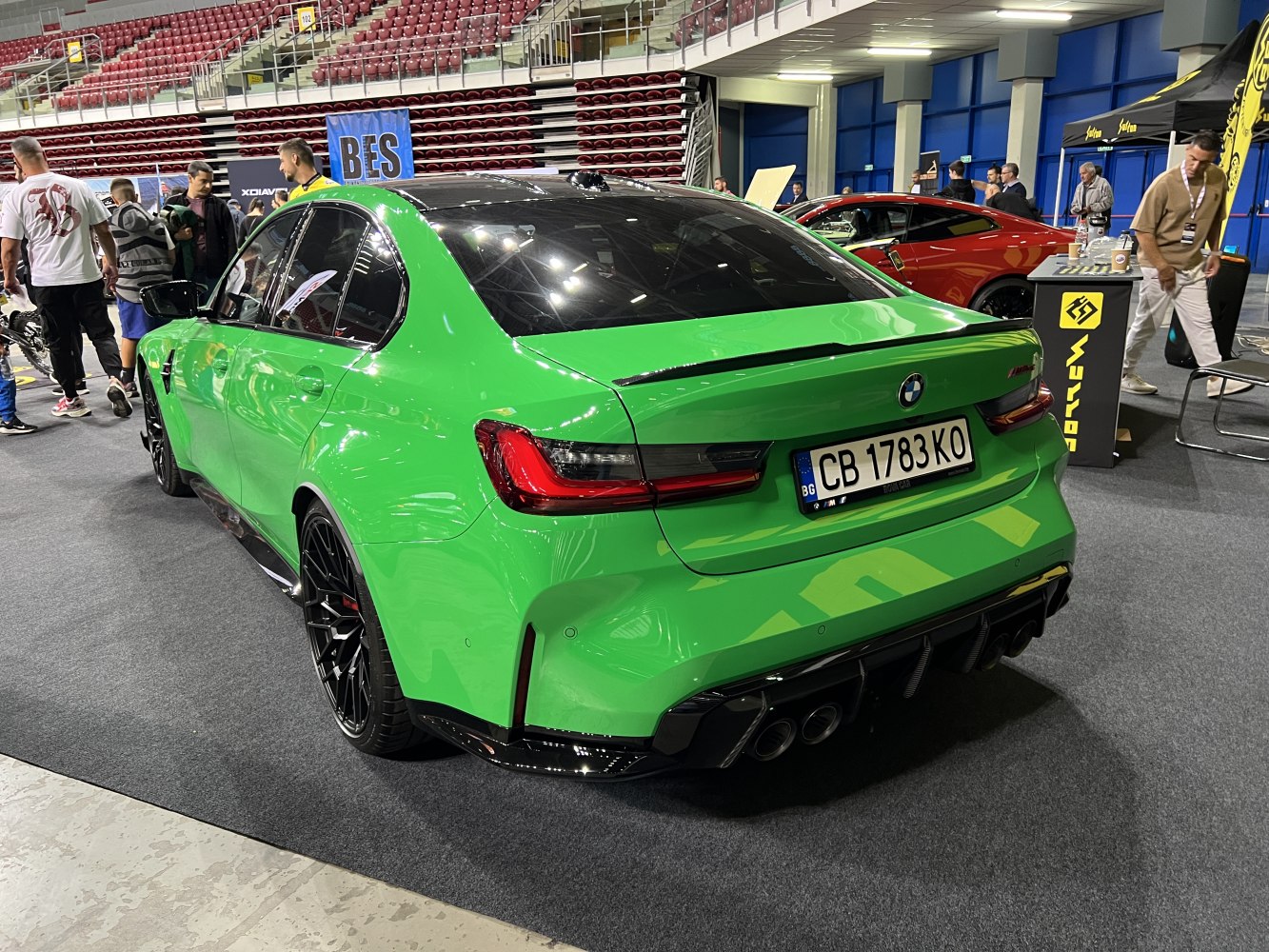 Rear-side view of green sedan with quad exhaust and black wheels