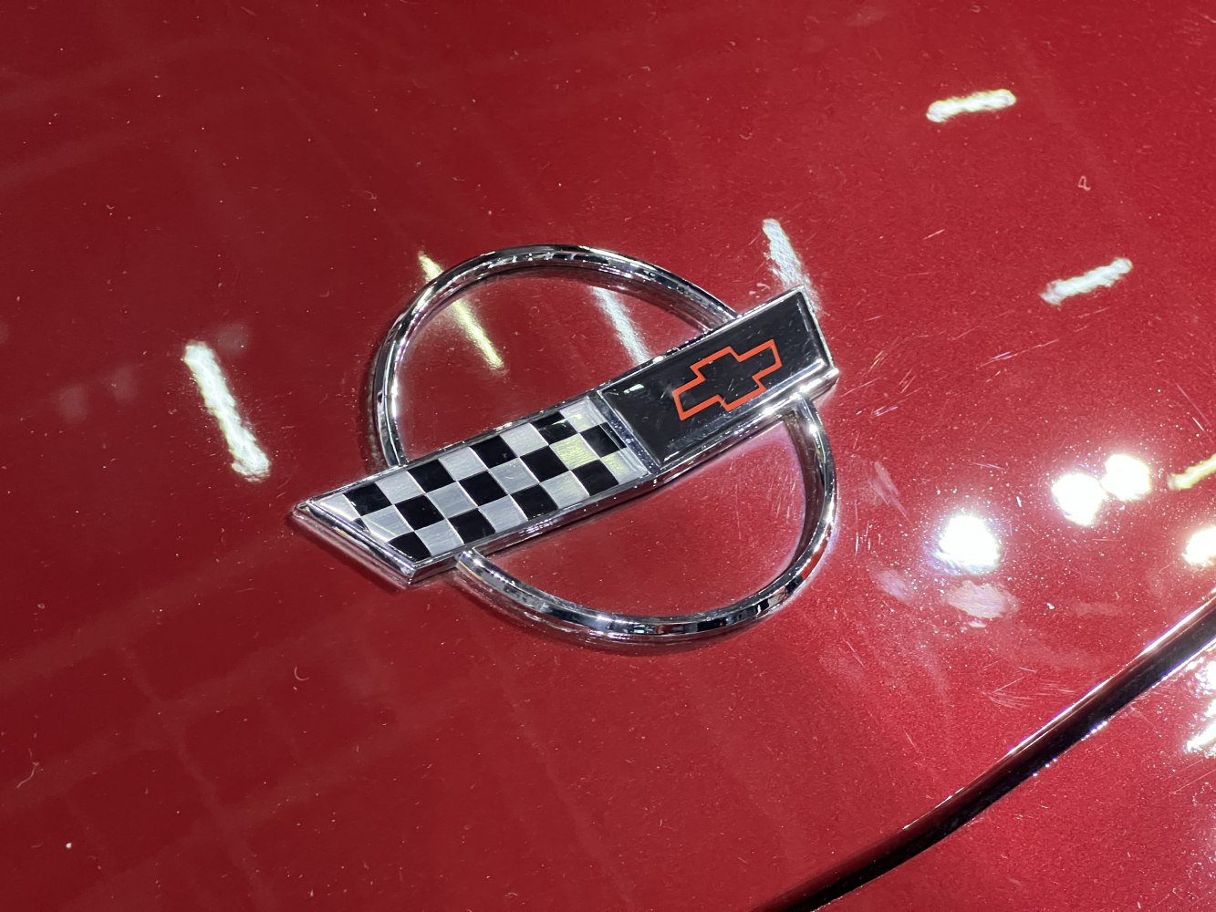 Close-up of Corvette C4 facelift hood emblem with checkerboard and bowtie design