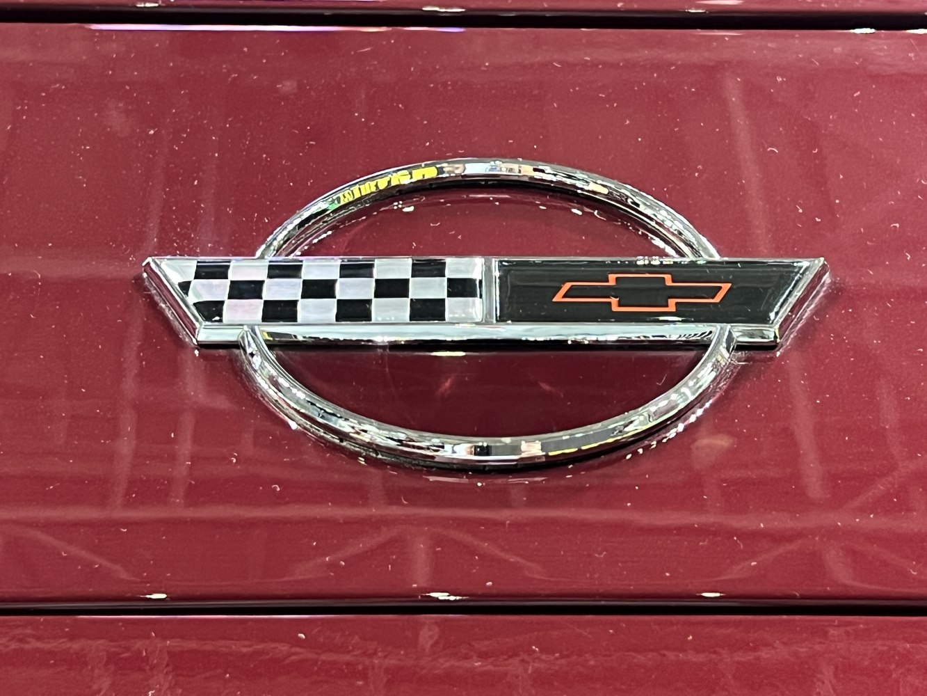 Close-up of Corvette C4 facelift emblem with checkered flag and bowtie logo