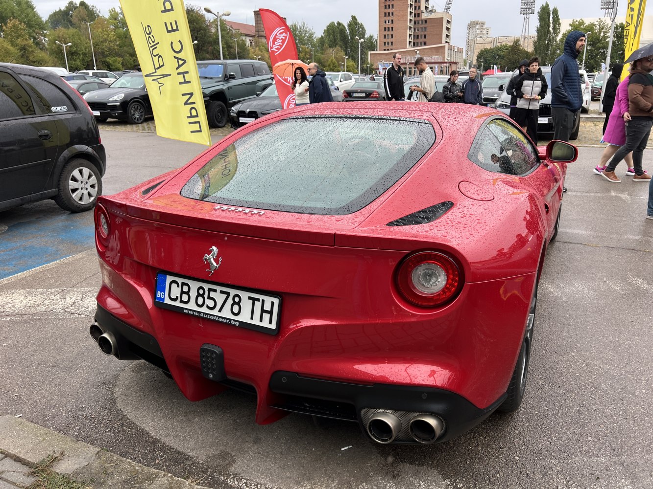 Red sports car rear with round taillights and quad exhaust pipes.