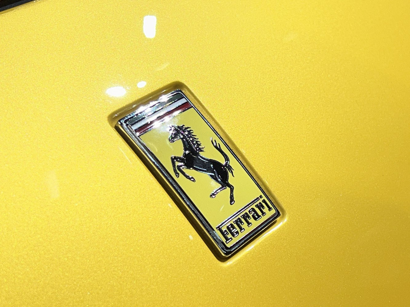 Close-up of Ferrari emblem on yellow surface