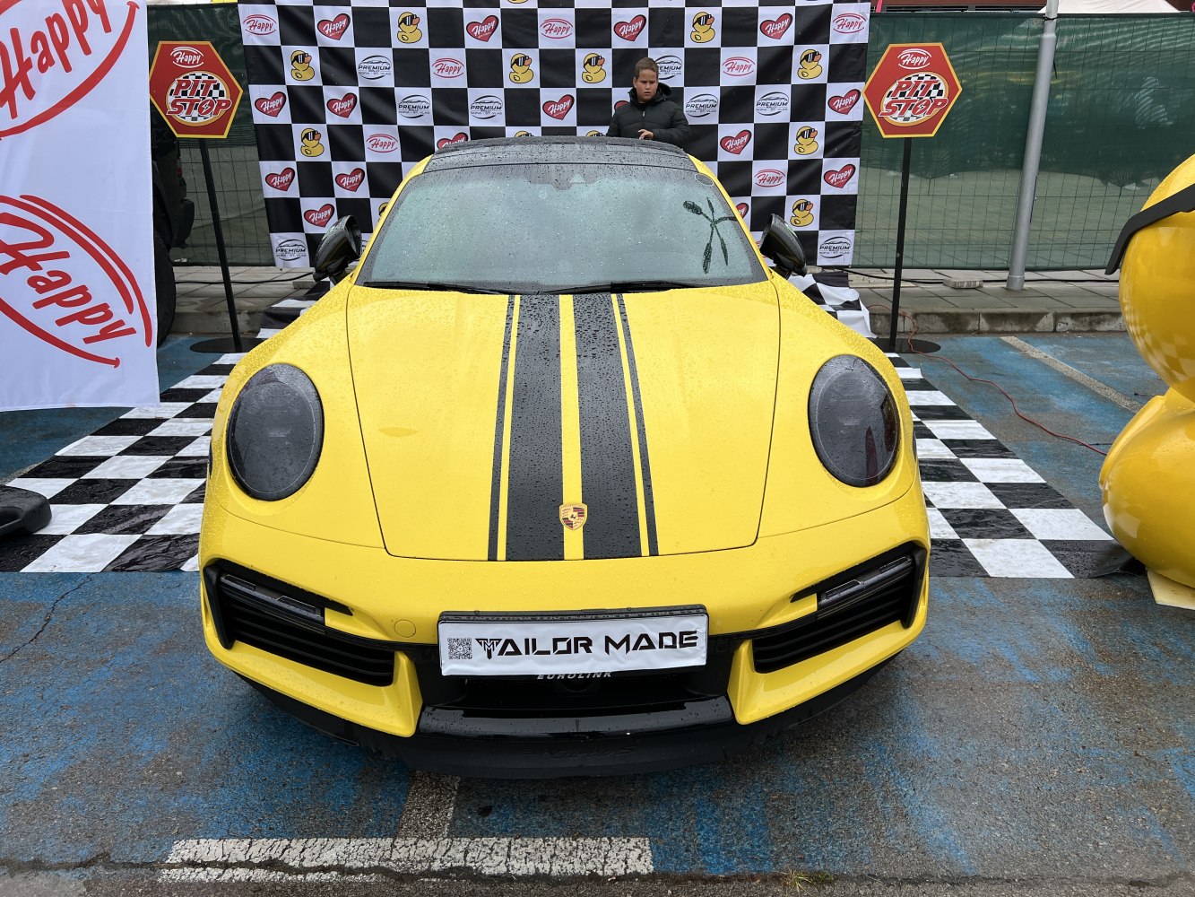 Close-up front view of yellow Porsche 911 with black racing stripes