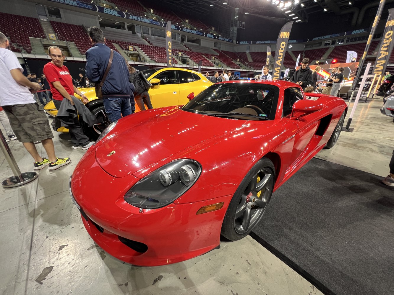 Red mid-engine sports car with distinctive dual round headlights and aerodynamic design.