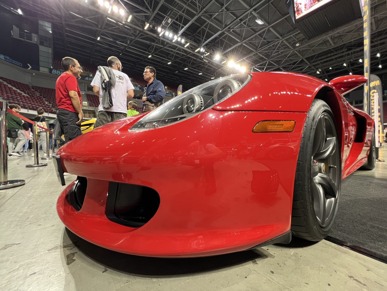 Close-up front view of red low-slung sports car with headlight and wheel focus