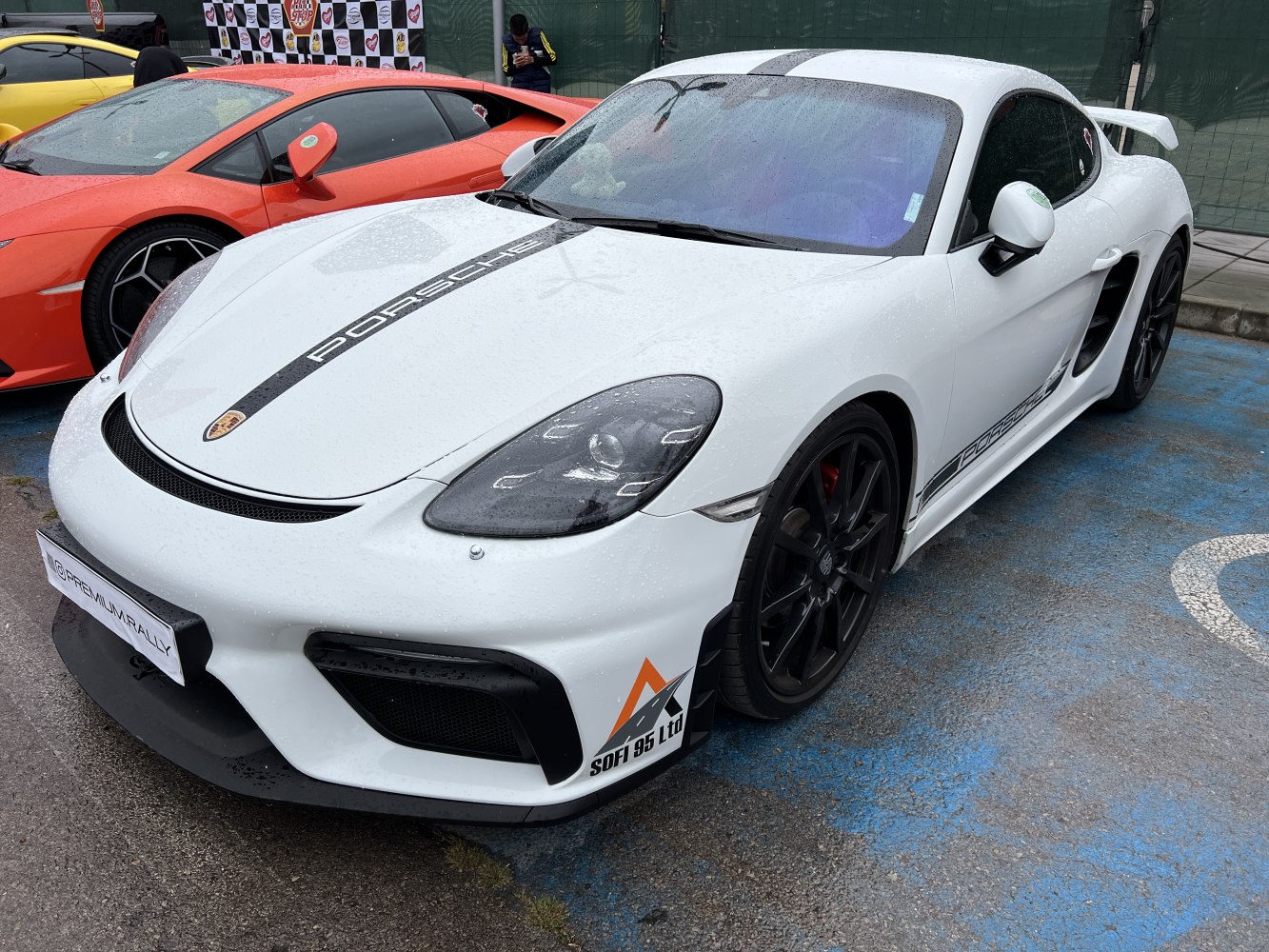 White sports coupe front-side in rain with black rims and racing decals