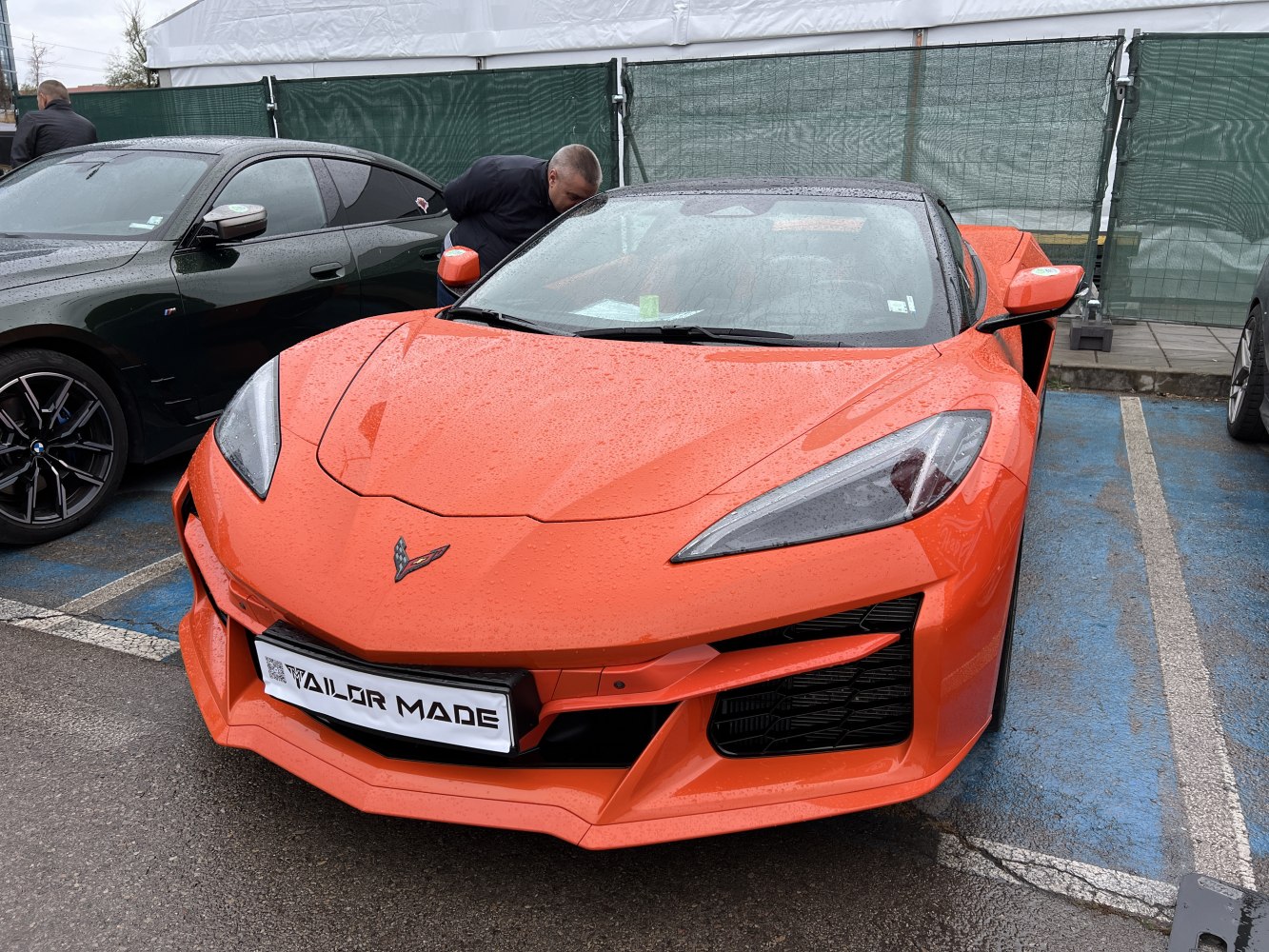 Front view of an orange mid-engine sports coupe with sharp headlights and aggressive grille