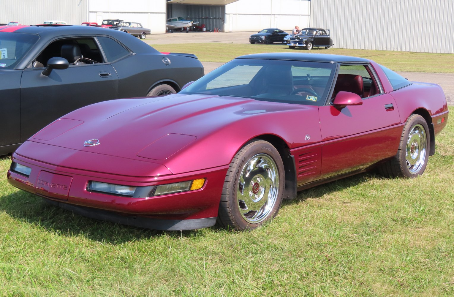 Front and side view of a metallic red sports coupe with chrome wheels.