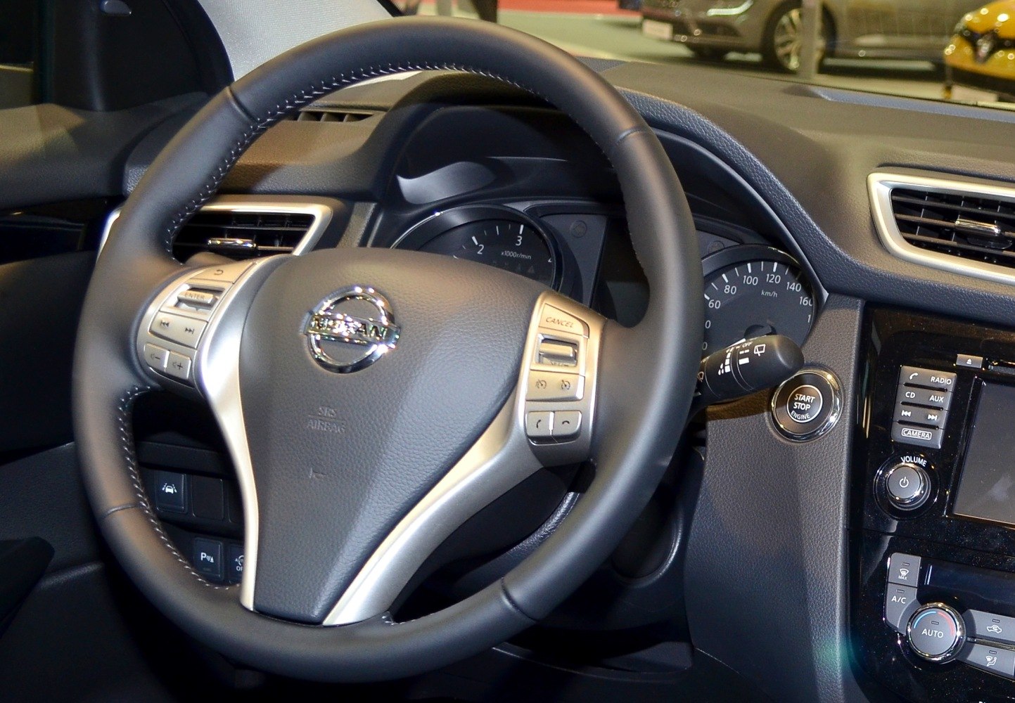 Steering wheel with control buttons and dashboard cluster.