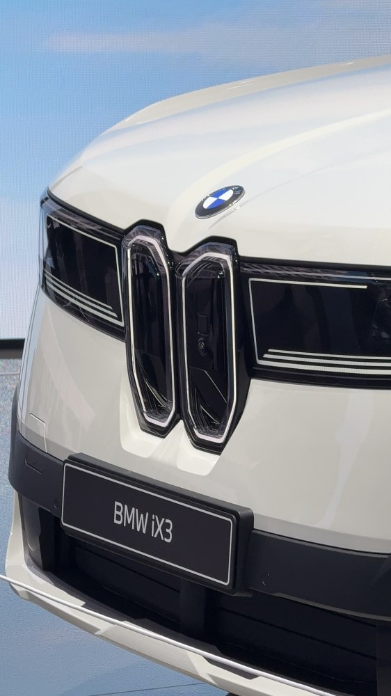 Close-up of 2026 BMW iX3 kidney grille and badge on front.