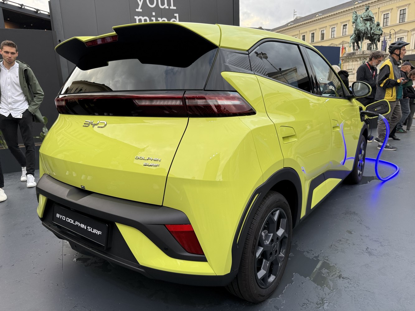 Rear view of a yellow electric hatchback charging with modern tail lights