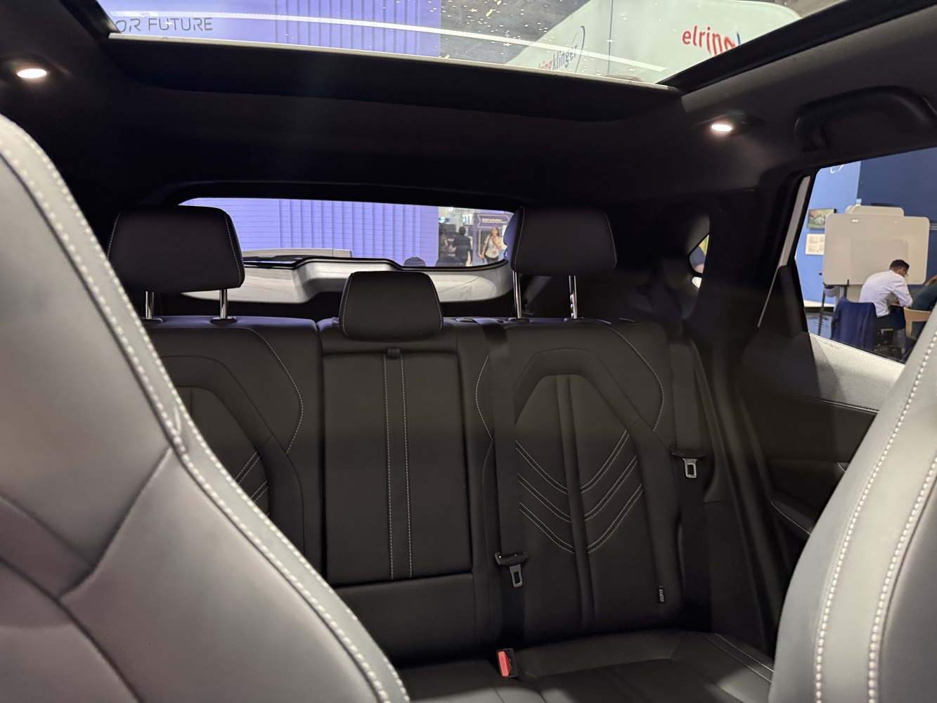 Black leather rear seats with stitching and panoramic sunroof inside car cabin
