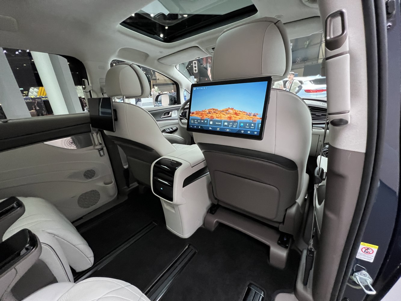 Rear passenger entertainment screens with spacious luxury seating and panoramic sunroof