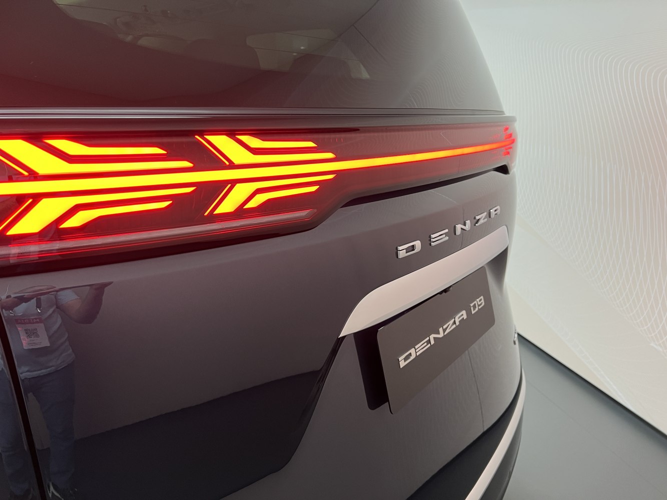 Close-up of rear LED tail light with emblem on a dark vehicle surface