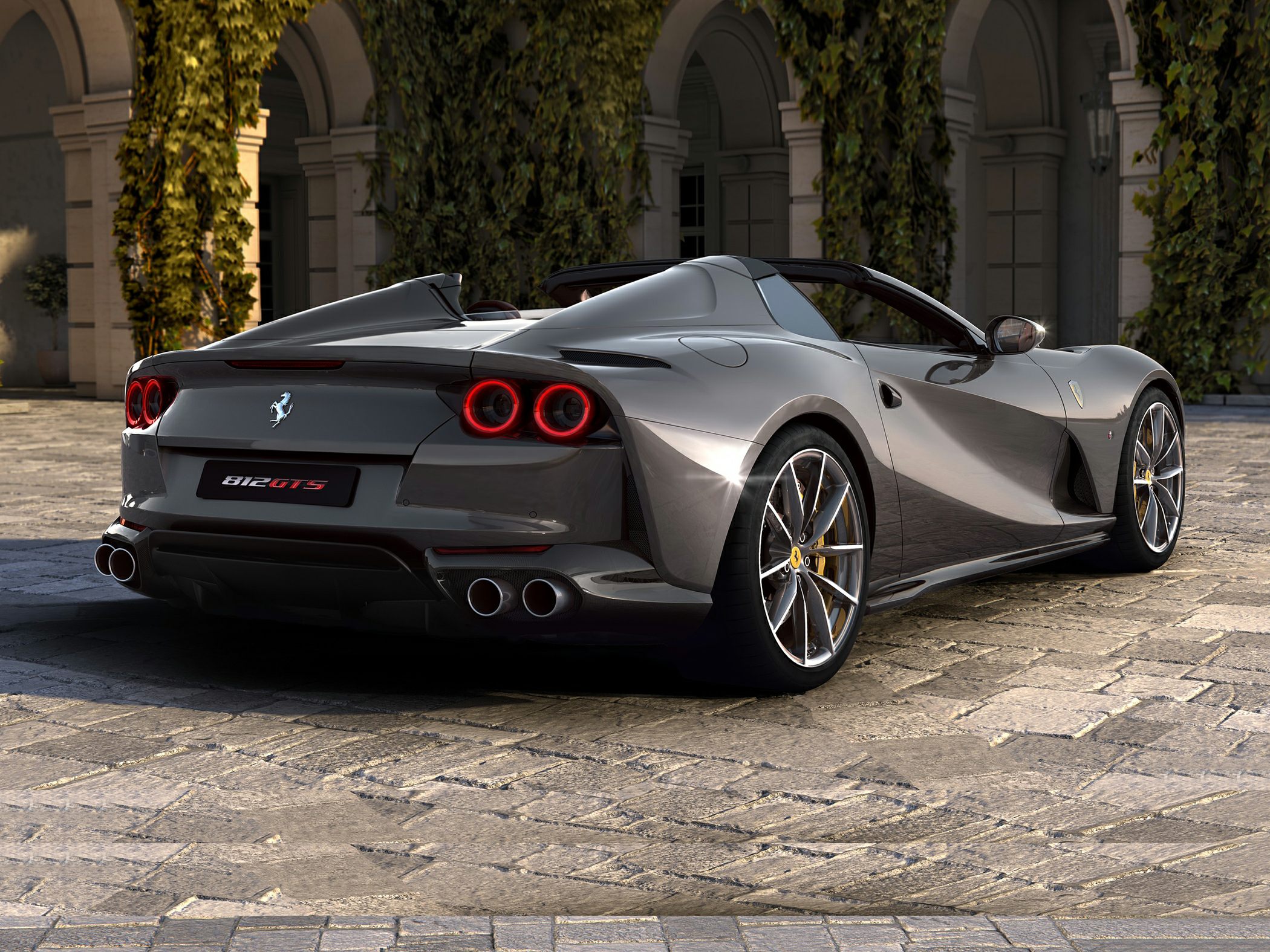 Rear and side view of a sleek convertible with quad exhausts and distinctive round taillights