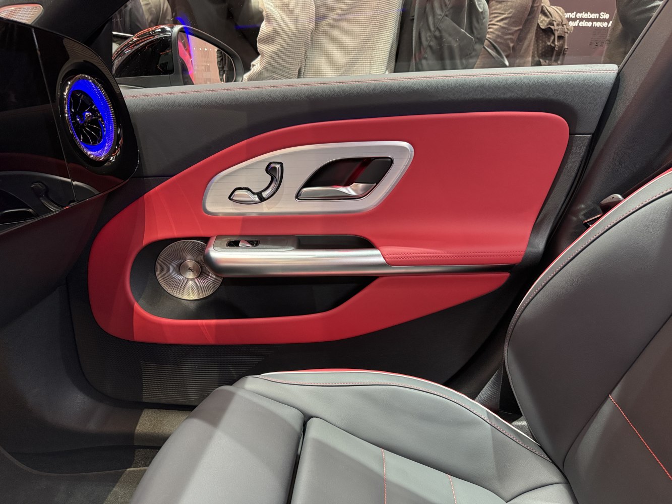 Red and black car door panel with metal handle and speaker