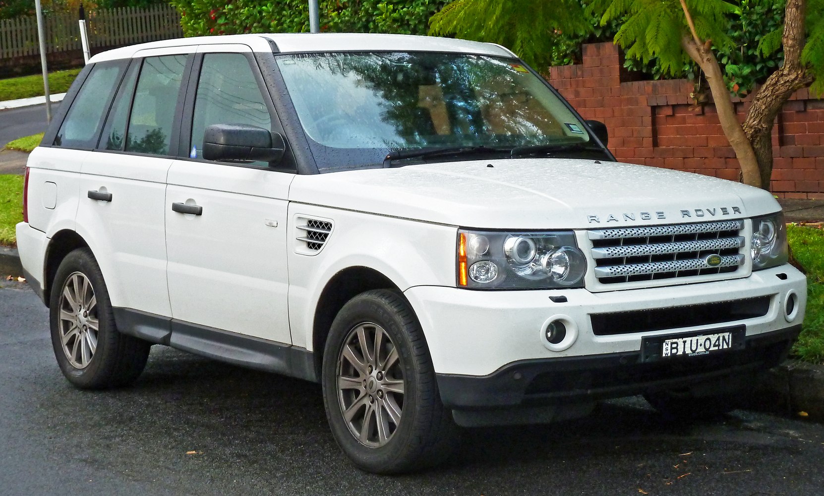 Front side view of SUV with distinctive headlights and alloy wheels on wet road