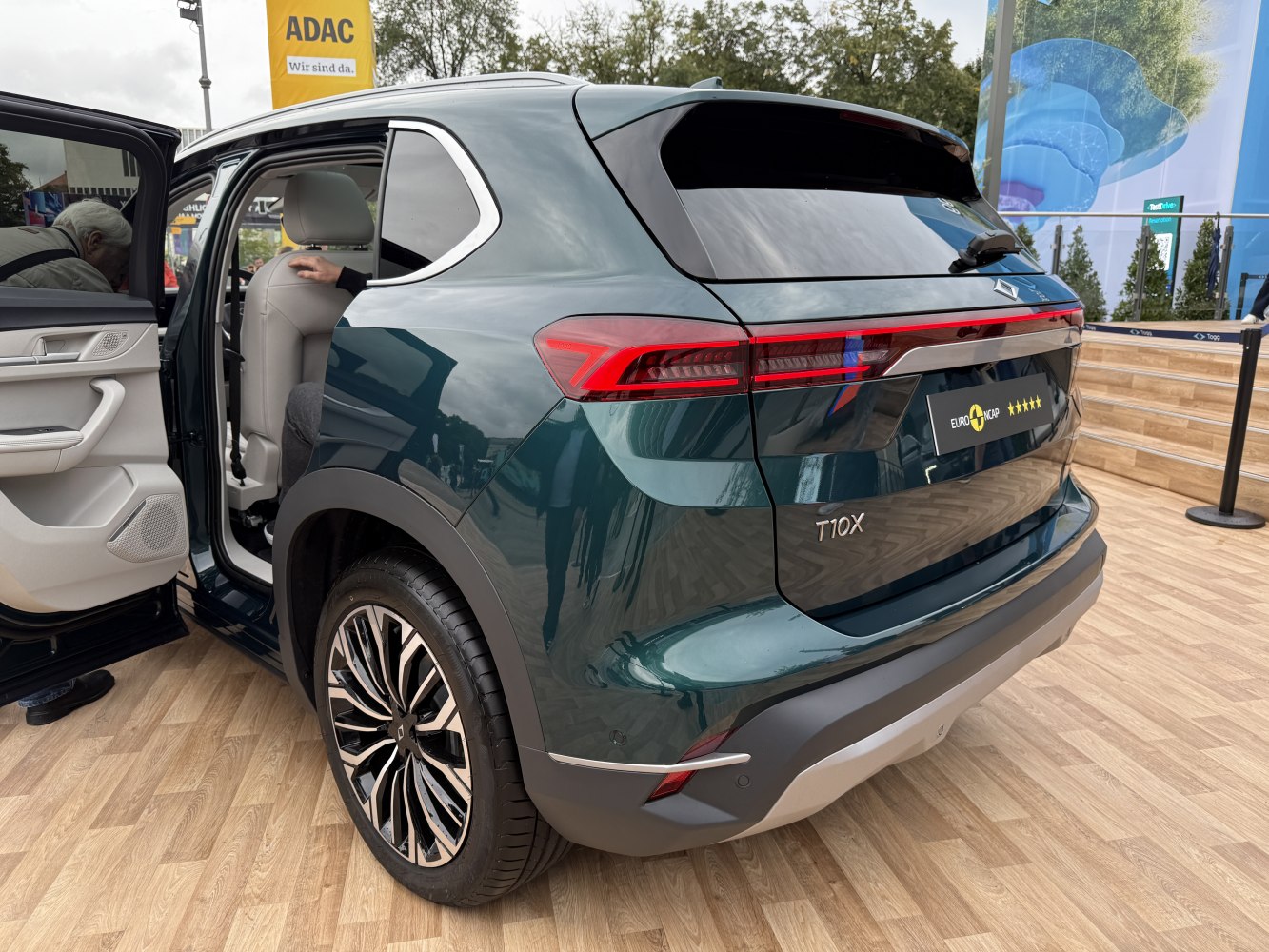 Rear view with distinctive taillights, open door, stylish wheel rims.