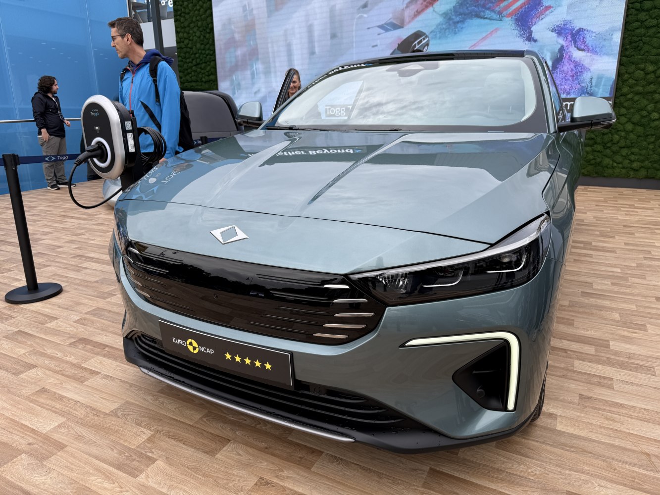 Front view of electric SUV with LED headlights and charging station