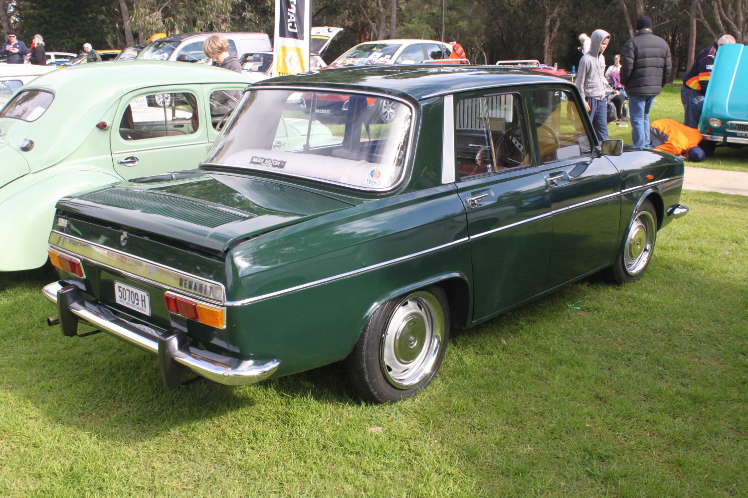 Rear and side profile of a classic green sedan with chrome bumper and vintage styling.
